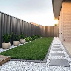 a backyard with grass and stepping stones on the ground, next to a fenced in area