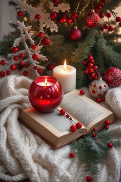 an open book with a lit candle next to it on a blanket near a christmas tree