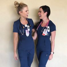 two women in scrubs are standing next to each other and smiling at each other