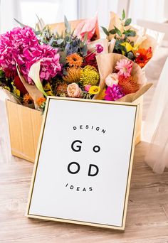 a box filled with lots of flowers sitting on top of a wooden floor next to a sign