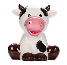 a ceramic cow sitting on the ground with its mouth open and tongue out, in front of a white background