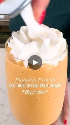 a person holding a glass with whipped cream in it and the text pumpkin protein cottage cheese milkshake