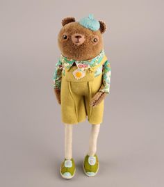 a teddy bear dressed in yellow pants and green shoes with a flower on his shirt