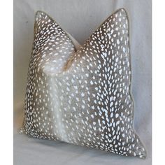 a white and brown pillow sitting on top of a white bed sheet covered in animal print