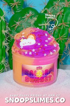 a pink and orange container with stars on it, next to cactus plants in the background