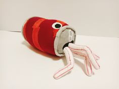 a red stuffed animal with long legs and big eyes sitting on a white counter top