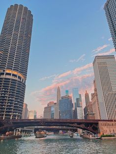 two tall buildings next to each other on the water with a bridge in front of them