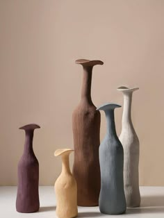 five different colored vases sitting on top of a table