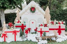 several presents are wrapped in red and white ribbon, with a gingerbread house behind them