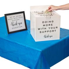 a donation box sitting on top of a table next to a sign that reads, doing more with your support