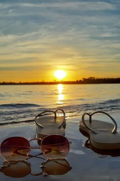 two pairs of sunglasses sitting on the beach at sunset