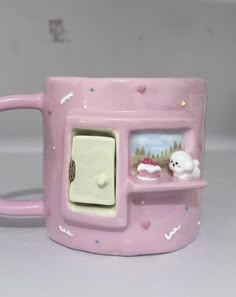 a pink coffee mug with an oven on the front and two white cats in the back