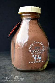 a glass jar filled with chocolate milk sitting on top of a gray countertop next to a black wall