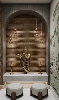 a room with two stools and a gold statue on the wall in front of it