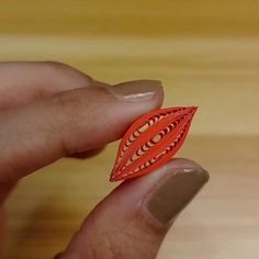 a hand holding an origami piece in it's left hand on a wooden surface