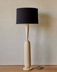 a wooden table lamp with a black shade on it and a pair of scissors next to it