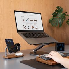 a person typing on a keyboard in front of a laptop and cell phone charging station