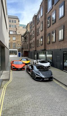 three exotic sports cars parked on the side of a street