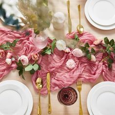 the table is set with white plates, goldware and pink flowered napkins