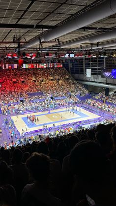 an indoor basketball game is being played in a stadium with people watching from the stands