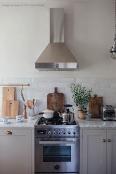 a stove top oven sitting inside of a kitchen next to wooden cutting boards and utensils