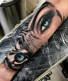 a person with blue eyes and an eyeball tattoo on their arm