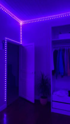 a room with purple lighting and clothes hanging on the closet doors in front of it