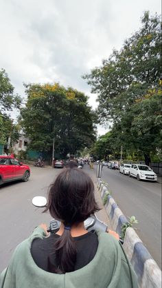 the back of a woman's head as she rides her motorcycle down the street