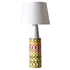 a lamp that is sitting on top of a white table cloth with a light shade over it