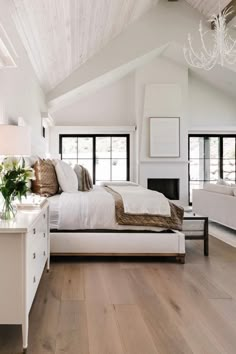 a bedroom with white walls and wood flooring has a large bed in the center