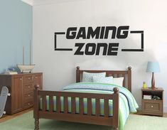 a bed room with a neatly made bed and a gaming zone wall decal