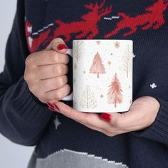 a woman is holding a coffee mug with christmas trees on it and santa's sleigh in the background