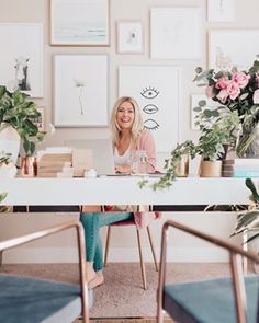 a woman sitting at a table with flowers in front of her and laptop on it