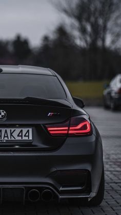 the back end of a black car parked in a parking lot