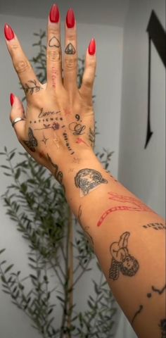 a woman's arm with tattoos on it and a plant in the corner behind her