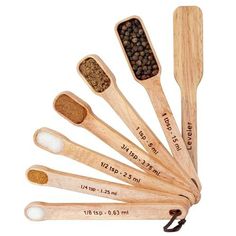 six wooden spoons with different types of seasoning in them and labeled on the sides