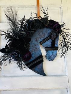 a blue and black wreath hanging on the side of a white door with dried flowers