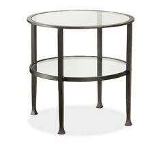 a round glass table with metal legs and a shelf on the bottom that holds two shelves