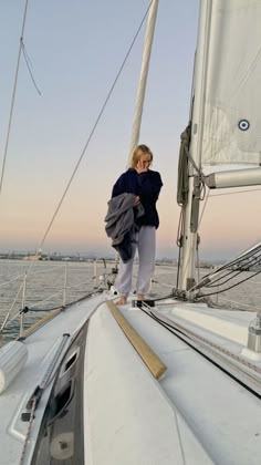 a woman standing on the deck of a sailboat