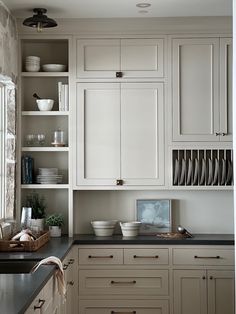 a kitchen filled with lots of white cupboards next to a counter topped with dishes