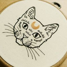 a close up of a cat with a crescent on it's face embroideryed onto a wooden hoop