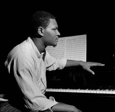 a man sitting at a piano with his hand on the keyboard and music sheets behind him