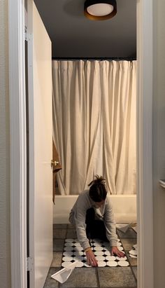 a man kneeling down on the floor in front of a bathroom mirror and toilet paper