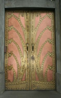 an ornately designed metal door with pink and gold paint on the front part of it