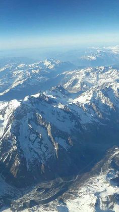 the view from an airplane looking down on snow covered mountains and valleys in the distance