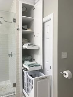 a bathroom with white cabinets and shelves filled with towels