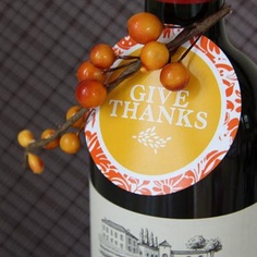 a bottle of wine with some oranges on top of it and a sticker that says give thanks