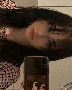 a woman with long black hair holding a cell phone in front of her face and wearing fishnet stockings