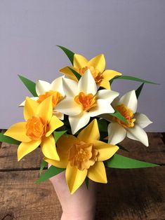 a vase filled with yellow and white flowers on top of a wooden table