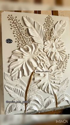 an intricately designed card with leaves and flowers on it, sitting on a table